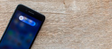 Songkhla, Hatyai, Tayland 28 Kasım 2020: Ekran iPhone 7 ve siyah renkli iPhone 7 'de elektriği kesmek için kaydırın, Apple iPhone 7' yi ahşap masadaki siyah ile kapatın. Kapanış fotoğrafçılığı, tasarım için alanı kopyala