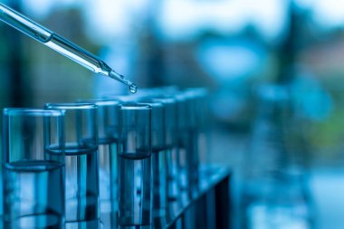 Kimyasal ve bilimsel deney kavramı. Yaklaş, sağdaki boşluğu kopyala. Bilim laboratuarlarında kimya deneyleri. Kimyasal maddeyi test tüpüne atın. Birçok test tüpü beyaz bir masaya yerleştirilir.