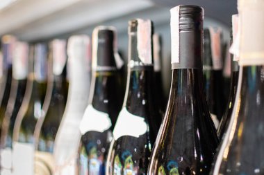 Şarap şişeleri bir mağazanın rafına konur. Partilerde, düğünlerde, doğum günlerinde, sevgililer gününde içki konsepti. seçici odak, kapat, boşluğu kopyala