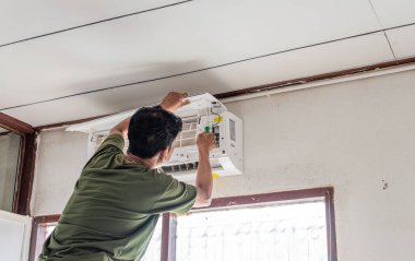 Binanın içinde tek bir adam çalışıyor. Teknisyen yaz mevsiminde yatak odasına klima kuruyor. Yaklaş Seçici Odaklanma. Bulanık Arkaplan