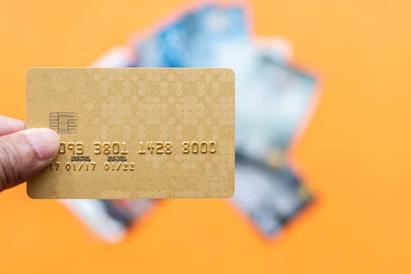 Businessman showing debit card online shopping, payment, online banking, money transfer, concept, selective focus, copy space, right. Closeup, man\'s hand holding credit card on orange, blur background