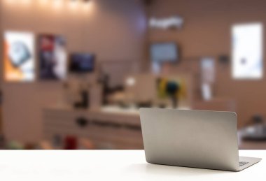 Dizüstü bilgisayarın arkası boş, beyaz bir masaya yerleştirilmiş ve hiç kimse, hiç kimse yok. Teknoloji iş konsepti, akıllı telefon, not defteri, internet, sol tarafta tasarım için kopya alanı, kapat, bulanık arkaplan.