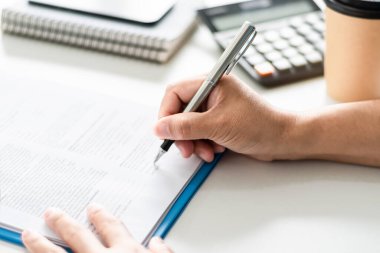 adult woman person hand holding pen writing or signing document on clipboard indoor at company, closeup finger professional businesswoman make signature agreement paperwork business corporate on desk