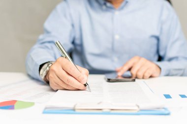 professional businessman hand holding pen writing and sign paperwork or document finance indoor at office, man manager person handwriting paper on clipboard and signature agreement approval business