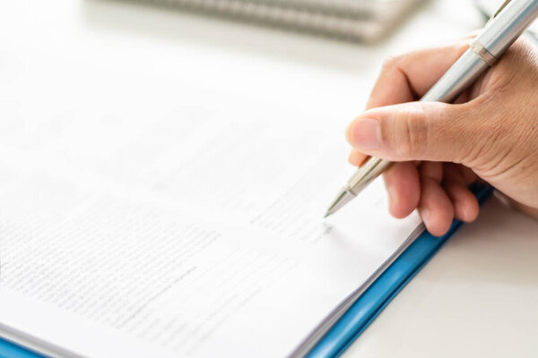 adult woman person hand holding pen writing or signing document on clipboard indoor at company, closeup finger professional businesswoman make signature agreement paperwork business corporate on desk