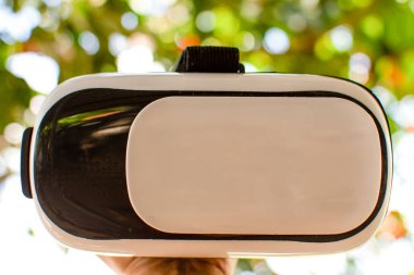 Sanal gerçekliği (VR) beyaz ve siyah tutan erkek eli. Man VR tek başına oynuyor. Yakın plan, bokeh ve bulanık arkaplan.