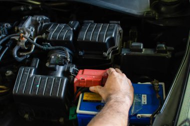 Motor bakımı kavramı. Teknisyen güç bataryasını kontrol ediyor. Adamların elleri arabalarının ana güç kaynaklarını ve elektrik sistemlerini inceliyor. DC 'nin gücü kesildi. Bulanık arkaplan