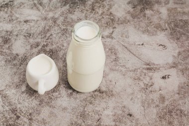 beverage liquid milk white fresh natural in a glass bottle on table drink to healthy has protein and calcium for child or toddler, nobody, closeup, cement background and copy space on right for content
