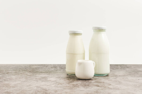 жидкое молоко жидкое белое свежее натуральное молоко в стеклянных бутылках на стол напиток для здорового имеет белок и кальций для ребенка или малыша, никто, крупным планом, белый фон и копировать пространство слева для содержания