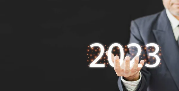 person businessman has happy hand holding the number new year 2023 is a symbol start a business finance economy growth investment and have profit in future, man has idea plan management money on 2023