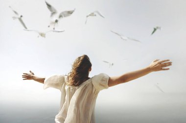 Gökyüzüne doğru açık kolları olan bir kadın özgürlük havası soluyor.