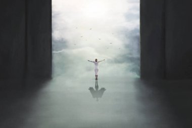 Kollarını gökyüzüne uzatmış bir kadın yerde kanatlarıyla sürrealist bir gölge oluşturur.