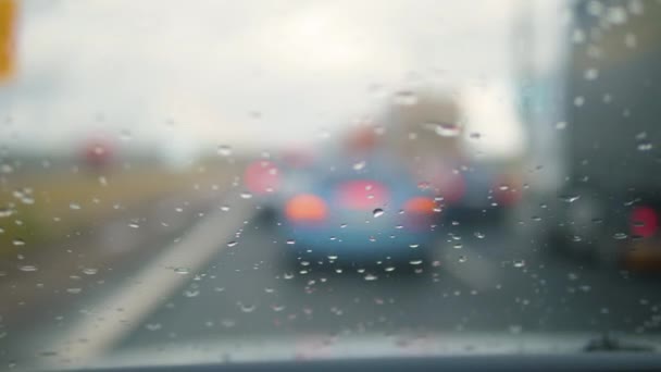 Närbild av regndroppar som rinner ner vindrutan på en bil — Stockvideo