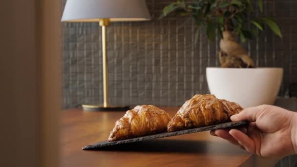 Två färska läckra croissanter placeras på ett träbord — Stockvideo