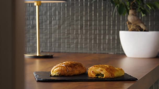 Dos deliciosos puffs con hierbas y queso se colocan en una mesa de madera — Vídeo de stock