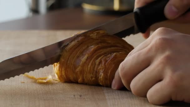 Close-up van het doormidden snijden van een verse croissant — Stockvideo