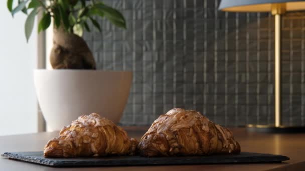 Dos deliciosos cruasanes frescos en una bandeja sobre la mesa — Vídeos de Stock