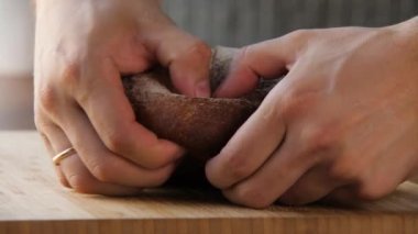 Yakın plan insan eli taze pişmiş ekmeği ikiye böler.