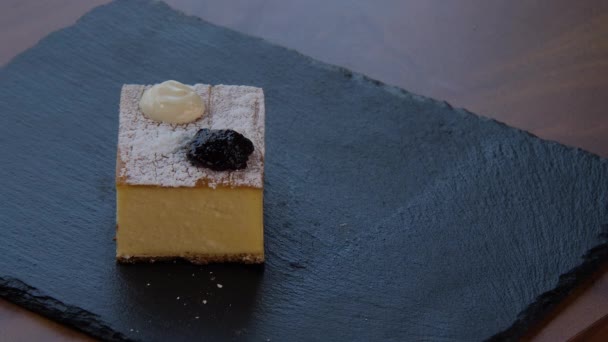 Blick von oben auf ein elegantes quadratisches Stück Käsekuchen — Stockvideo