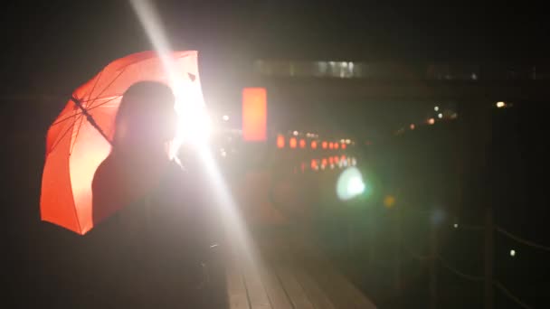 Портрет женщины, стоящей под ярко-красным зонтом — стоковое видео
