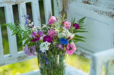 Renkli yabani çiçek buketi beyaz bir bahçe bankında yaz bahçesinde