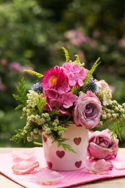 Colorful flower bouquet with roses in a coffee cup on a table