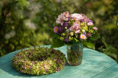 Bahçe masasında çiçek çelengi olan çiçek buketi.