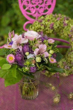 Bahçe masasında çiçek çelengi olan çiçek buketi.