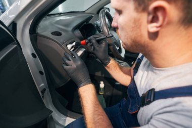 Beyaz adam araba panelini yakın çekimde temizliyor. İç yıkama.