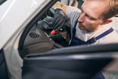 Araba tamiri. İşçi otomobil başı paneli kapatılıyor