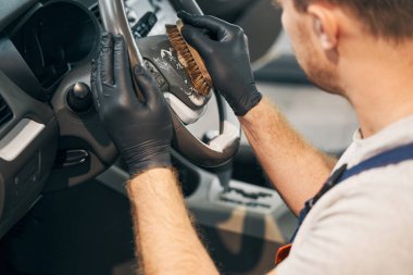 Araba servisi çalışanı direksiyon köpüğüyle kimyasal araba yıkama yapıyor.