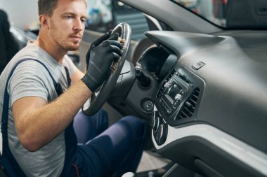 Tamirci, direksiyon ve gösterge panelini dezenfektanla yıkıyor.