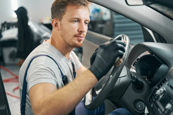 Servis çalışanı tekerleği temizler, yan görünümlü dezenfektanlı gösterge paneli