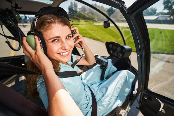 Gülümseyen kadın pilot uçuştan önce kulaklık takıyor.