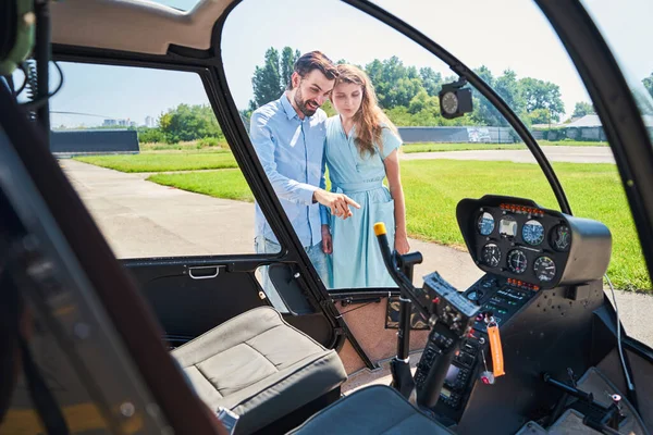 Özel helikopterini kadınlara gösteren memnun bir adam.