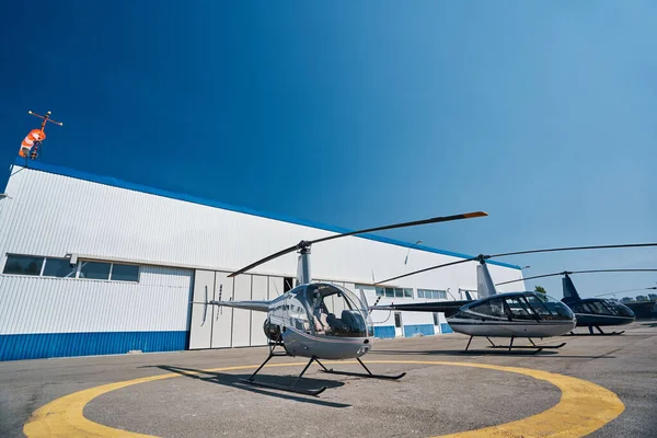 Вертолеты припаркованы на вертолетной площадке у металлического ангара — стоковое фото
