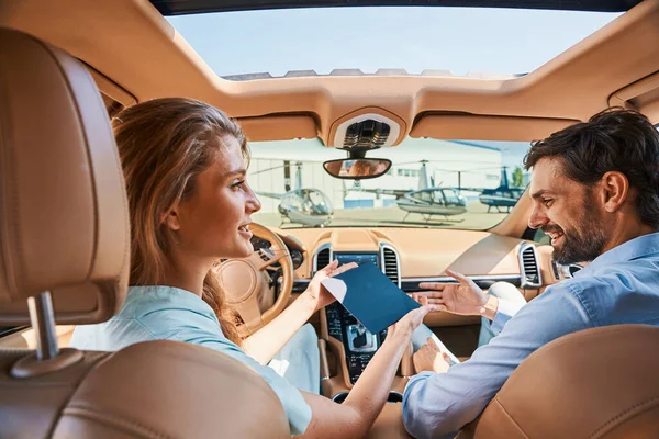 Couple sitting in car parked before helipad — Stock Photo, Image