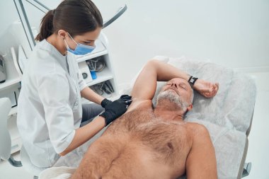 Erkek kişi kozmetoloji kliniğinde koltuk altı enjeksiyonu alıyor.