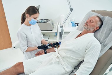 Kadın doktor klinikteki adamdan kan örneği alıyor.