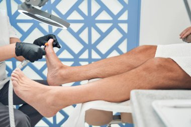 Pedikürcü erkek müşteri için donanım pedikürü yapıyor