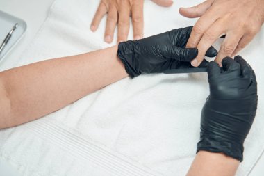 Manikürcü elleri tırnak törpülüyor.