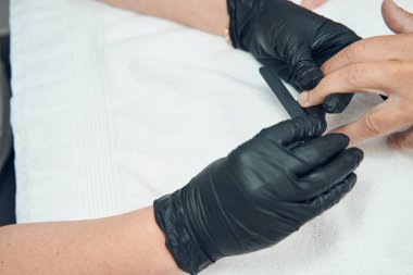 Güzellik uzmanı elleriyle tırnak törpülüyor.