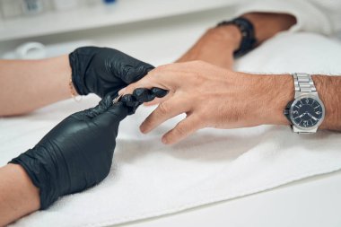 Manikürcü manikürcülerle parmak derisini kesiyor.