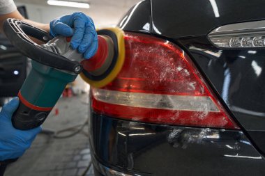 Araba tamircisi. Stüdyonun parlak kırmızı lambasını temizliyor.