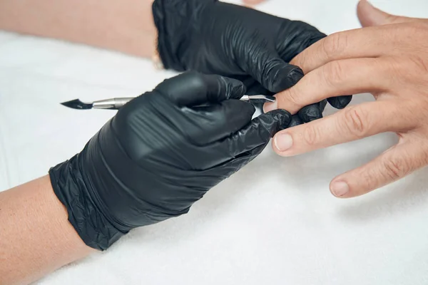 Manicura maestro la eliminación de la cutícula en el dedo del hombre con herramienta de metal —  Fotos de Stock