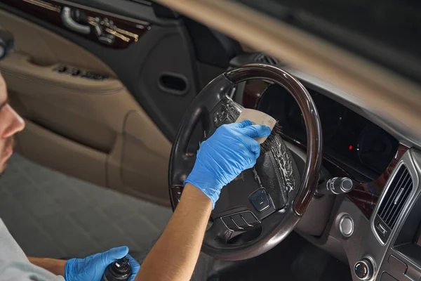 Imagen recortada de trabajador pulido volante del coche en el interior — Foto de Stock