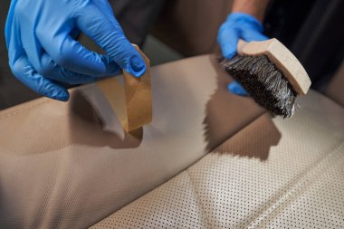 Stüdyo çalışanı, arabanın içini fırçayla temizliyor.