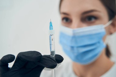 Kadın doktor kozmetolojist ameliyat için şırınga tutuyor.