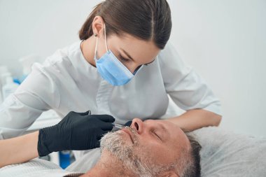 Adam kozmetoloji kliniğinde yaşlanmayı önleyici iğne yaptırıyor.