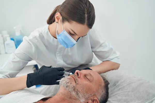 Medico cosmetologo fare iniezione in faccia all'uomo — Foto Stock